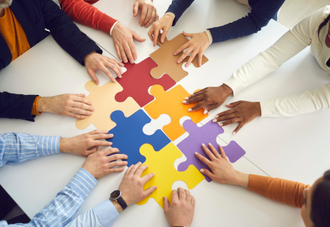 different hands putting puzzle pieces together on a table